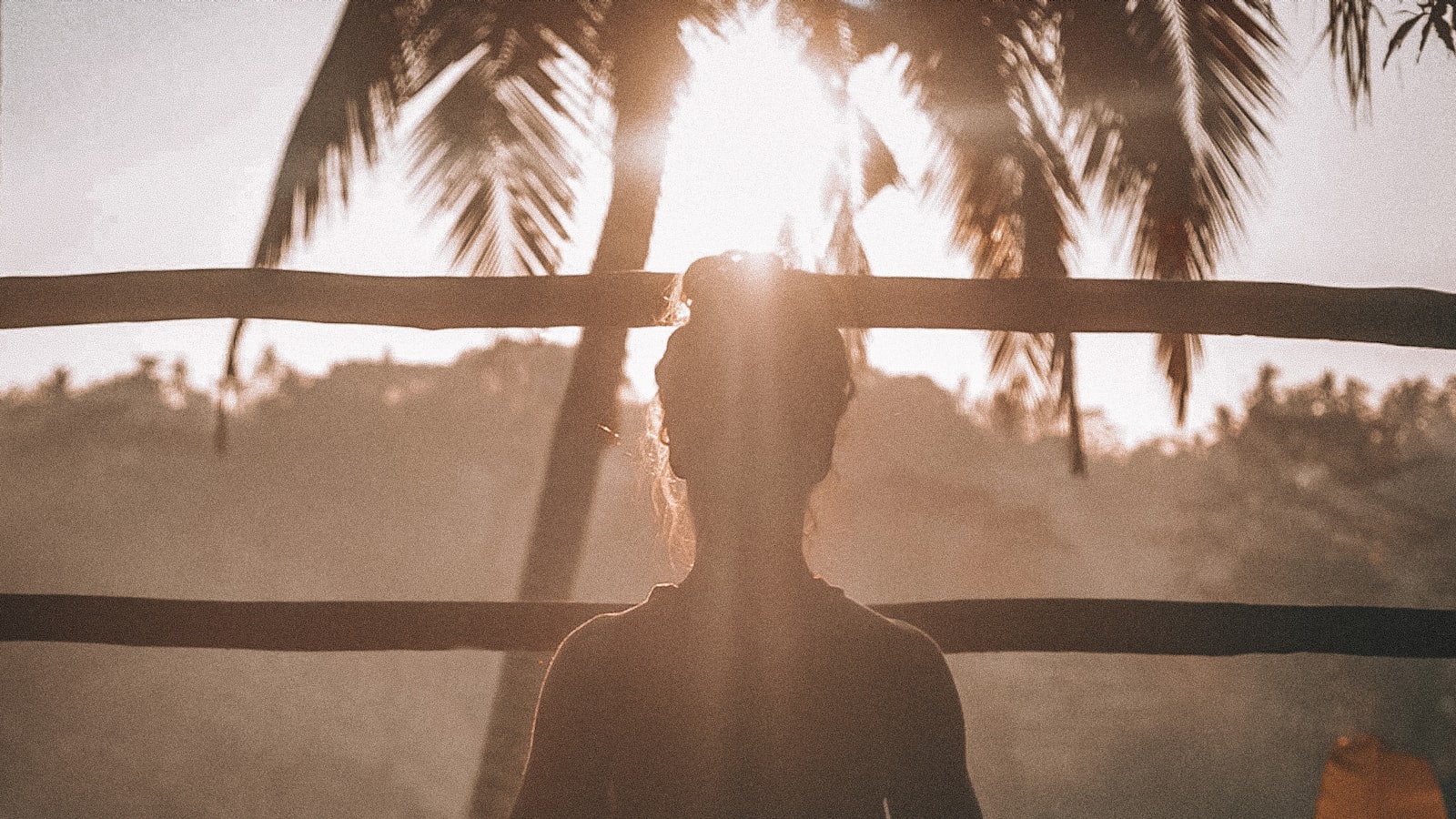A person standing outdoors at sunset with arms raised, taking a break
