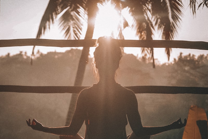 A person standing outdoors at sunset with arms raised, taking a break