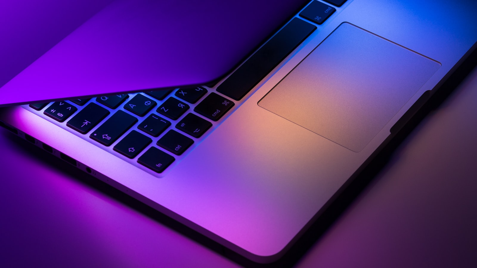 A laptop on a desk in low light with code on the screen
