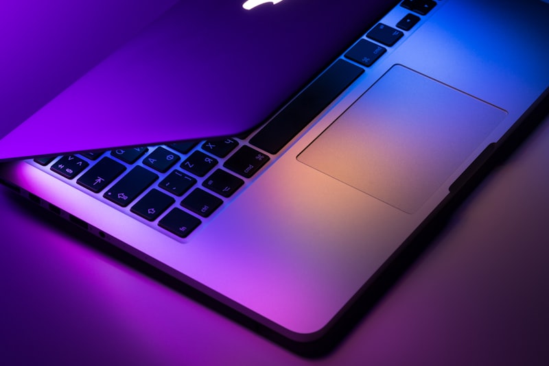 A laptop on a desk in low light with code on the screen