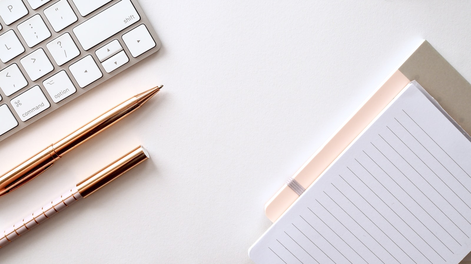 A minimal white keyboard and accessories on a white surface