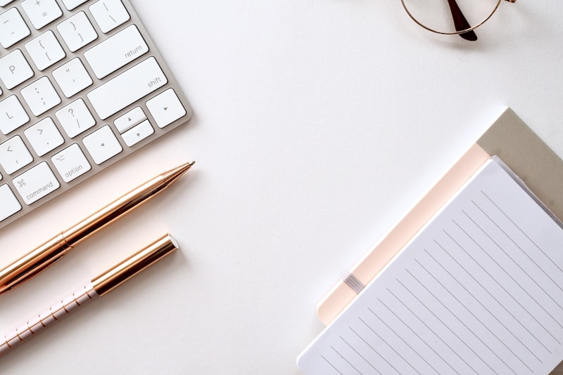 A minimal white keyboard and accessories on a white surface
